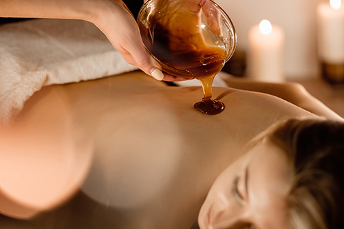 Hands of a cosmetologist pour honey coffee mixture on the client