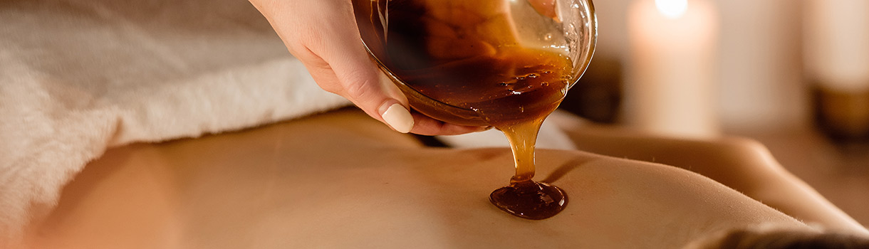 Hands of a cosmetologist pour honey coffee mixture on the client
