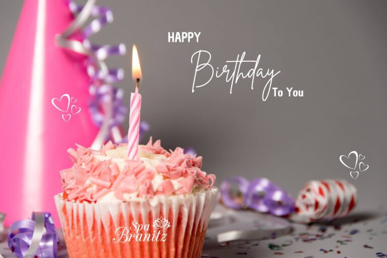 Ein rosa Cupcake mit brennender Kerze steht vor Partyhüten und buntem Konfetti